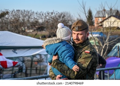 Medyka, Poland, March 2022: Polish soldier carries a refugee baby. Refugees from Ukraine escaping from war. Ukrainian refugees on crossing the border to Poland. Ukrainians fleeing the war.
