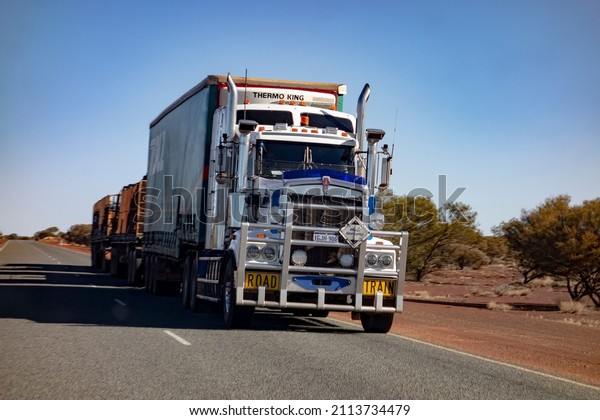 MEEKATHARRA, WESTERN\
AUSTRALIA - JULY 11, 2018: White Kenworth heavy road train truck\
transporting heavy stuff with  three trailers in Western Australia\
with motion blur\
effect