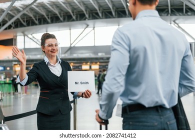 Meet By The Woman With Text. Young Businessman In Formal Clothes Is In The Airport At Daytime.