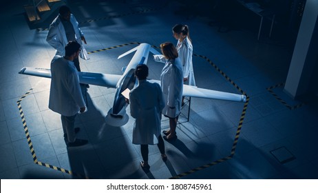 Meeting of Aerospace Engineers Work On Unmanned Aerial Vehicle Drone Prototype. Aviation Scientists in White Coats Talking. Industrial Laboratory with Surveillance or Military Aircraft. Elevated Shot - Shutterstock ID 1808745961