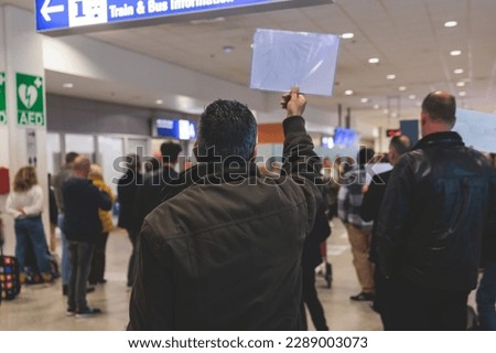 Meeting at the airport, person holding a placard card sign with welcome title text, greeting passenger on arrival, holding a name plate to receive a traveler, arrival area at international terminal