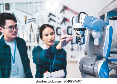 Meeting asian Engineers Maintenance Robot Arm at Lab. they are in a High Tech Research Laboratory with Modern Equipment. Technology and Innovation Concept.Professional Japanese Development Engineer .