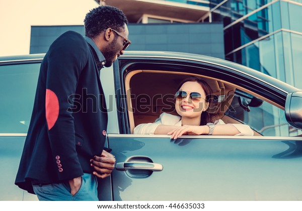Meeting of black casual man and  business woman near
a car.
