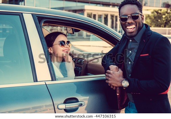 Meeting of black casual man and  business woman near\
a car.