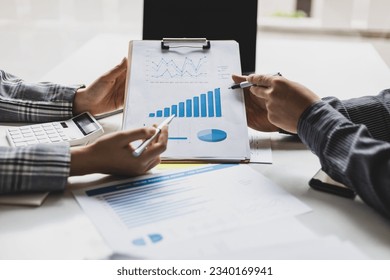 Meeting with business partners to discuss financial advisors to analyze market growth charts in business reports and plan investment strategies. - Powered by Shutterstock