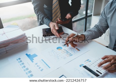 Meeting of businesspeople point to graph and chart to analyze market data, balance sheet, accounts, net profit to devise new sales strategies to increase productivity.