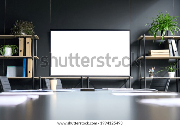 Meeting conference room with blank empty mockup\
tv screen monitor for advertising standing in modern contemporary\
office on black wall background. No people. Business technologies\
concept.
