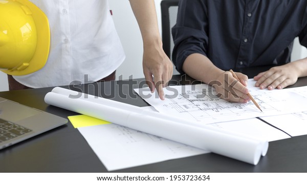 Meeting of engineers and architects in\
building planning, Consulting and brainstorming experts in\
architectural planning using blueprints, tape measure, rulers,\
laptop in designing\
buildings.