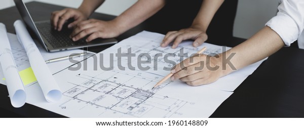 Meeting of engineers and architects in\
building planning, Consulting and brainstorming experts in\
architectural planning using blueprints, tape measure, rulers,\
laptop in designing\
buildings.