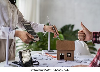 Meeting of female engineers and developers of renewable energy systems with solar panels and tabletop model houses. to design the use of renewable energy with wind turbines and solar - Powered by Shutterstock