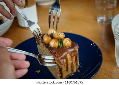 Meeting Friends And Sharing Or Eating Tasty Sweetness Dessert, A Piece Of Macademia Caramel Cake In Dark Blue Plate On Oak Wood Table In Cafe Restaurant On Weekend, Spend Time With Good Friends