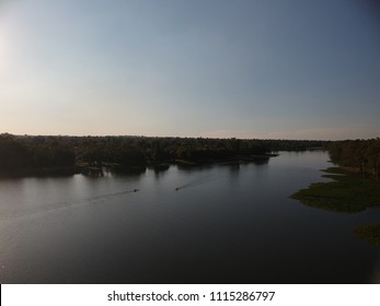 Meeting Half Way, 2 Canoes Travel In Opposite Directions On A Lake At Sunset