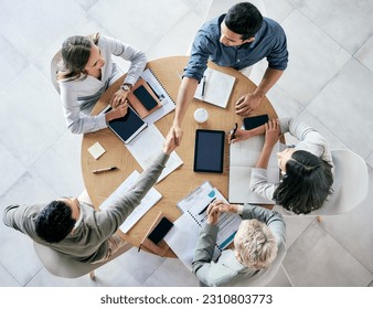 Meeting, handshake and overhead with a business team sitting around a table in the office at work. Partnership, thank you and welcome with male colleagues shaking hands in agreement of a b2b deal - Shutterstock ID 2310803773