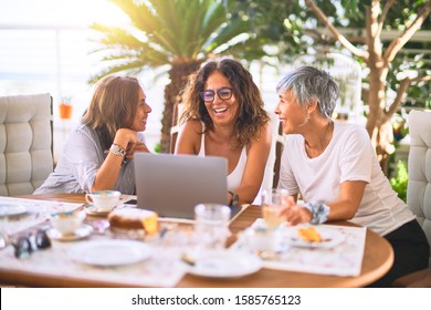 Meeting Of Middle Age Women Having Lunch And Drinking Coffee. Mature Friends Smiling Happy Using Laptop At Home On A Sunny Day