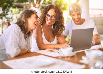 Meeting Of Middle Age Women Having Lunch And Drinking Coffee. Mature Friends Smiling Happy Using Laptop At Home On A Sunny Day