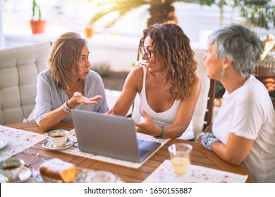 Meeting Of Middle Age Women Having Lunch And Drinking Coffee. Mature Friends Smiling Happy Using Laptop At Home On A Sunny Day