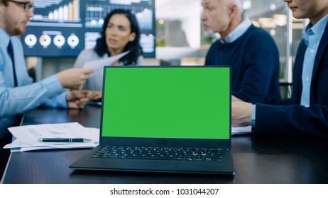 In the Meeting Room Laptop with Green Chroma Key Screen on the Conference Table. In the Background Business People Have Important Discussion. - Powered by Shutterstock