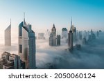 Mega tall skyscrapers of Dubai covered in early morning think fog. Rare aerial perspective. 