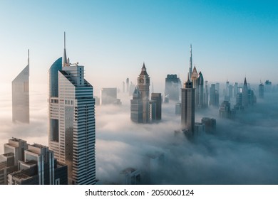 Grandes rascacielos altos de Dubái cubiertos por la madrugada de pensar niebla. Perspectiva aérea rara. 