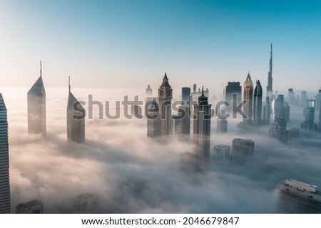 Mega tall skyscrapers of Dubai covered in early morning think fog. Rare aerial perspective. 