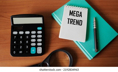 MEGA TREND, Text Written In A Notepad On A Wooden Table With A Calculator, Pen, Magnifier And Diary