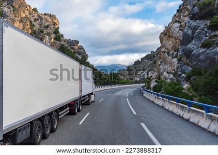 Mega truck or euro modular system (EMS) with refrigerated semi-trailers driving through a gorge.