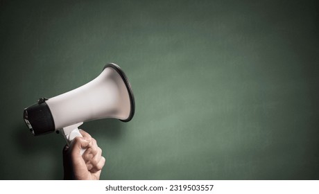 Megaphone loud hailer in front of green chalkboard announcement background with copy space - Shutterstock ID 2319503557