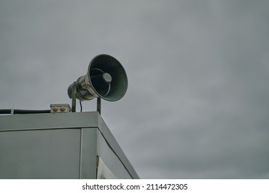 Megaphone On Cloudy Sky Background. Emergency Alert Siren. City Hazard Warning System. Providing Security In Town, Notification Of Emergencies. Copy Space For Text.