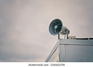 Megaphone on cloudy sky background. Providing security in town, notification of emergencies. Emergency alert siren. City hazard warning system. Copy space for text.