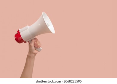 Megaphone in woman hands on a pink background. Copy space. 