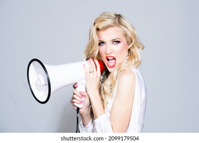 Megaphone and women. Portrait of pinup girl shouting. Young excited blonde fun woman screaming hot news, shouting aside in megaphone hurry up, isolated on color background studio.