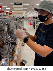 Melaka, Malaysia February 12,2021: Young Asean Man Doing Kitchen Tools Shopping During Covid19 Pandemic While Wearing Facemask And Plastic Glove For Protection Of The Virus