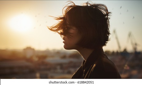 Melancholic beautiful portrait profile. Young girl, autumn mood, birds in the city sky. The port is abrasive against the background. Romantic affecting mood
