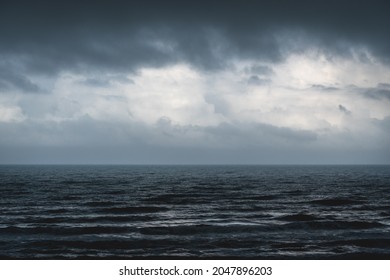 Melancholic dark blue seascape with silver shining rough waves during storm