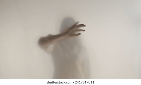 Melancholic female silhouette behind a transparent frosted curtain or glass close up. A woman is guiding her hand on the surface of the curtain. - Powered by Shutterstock
