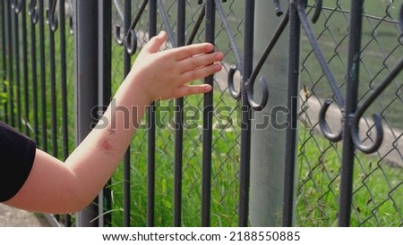 Melancholic Young Caucasian Girl Touching Metal Fence Bars with Fingers