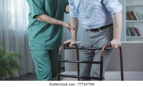 Melancholy Man Standing Up And Moving With Walking Frame At Nursing Home