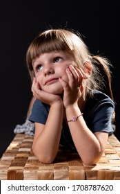 Melancolic Brown Haired Caucasic Child Lying On A Wooden Basket.