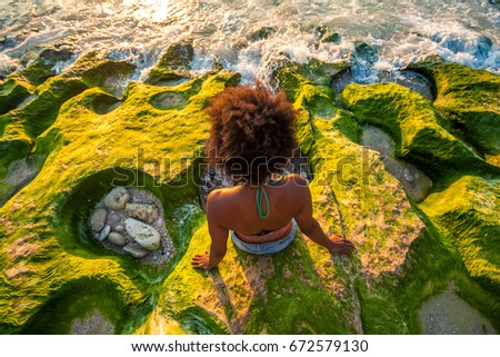 Melanesian pacific islander athlete girl with strong arms on coral reef at sunset