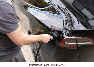 Melbourne, Australia - 15th September 2022: A Man Plugging In A Tesla Brand Electric Car To A Home EV Charging Plug