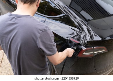 Melbourne, Australia - 15th September 2022: A Man Plugging In A Tesla Brand Electric Car To A Home EV Charging Plug