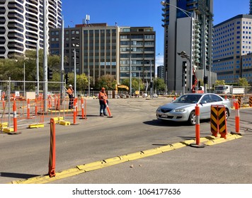 Melbourne, Australia: April 08, 2018: A Workman Watches The Entrance To The Construction Site During The Scheduled Maintenance Program On St Kilda Road. He Is Wearing A Hard Hat And Hi Viz Vest.