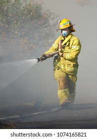 Melbourne, Australia - April 13, 2018: Fire Fighter Spraying Water On A Bush Fire In An Suburban Area Of Knox City In Melbourne East.