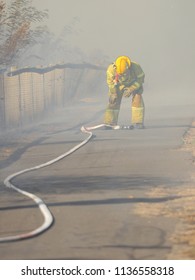 Melbourne, Australia - April 13, 2018: Fire Fighter With A Hose At A Bush Fire In An Suburban Area Of Knox City In Melbourne East.