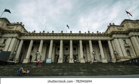 MELBOURNE, AUSTRALIA - DECEMBER 19, 2017: Tourists Sit On The Steps Of The Parliament House Of The State Of Victoria, An Example Of Neoclassical Architecture Dating Back To 1855.