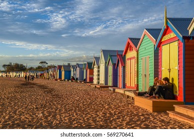 MELBOURNE, AUSTRALIA - JULY 18, 2016 : Tourists sit on deck of bathing boxes at Brighton Beach near Melbourne, Australia.