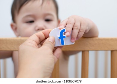 Melbourne, Australia - June 5, 2018: Parent Hand Give Facebook Sign To The Baby In Crib 