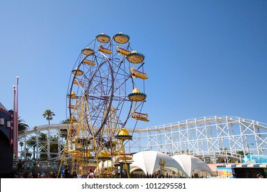 Melbourne, Australia: March 18, 2017: The Ferris Wheel At Melbourne's Luna Park. The Historic Amusement Park Located On The Foreshore Of Port Phillip Bay In St Kilda Was Opened In 1912. People Walk By