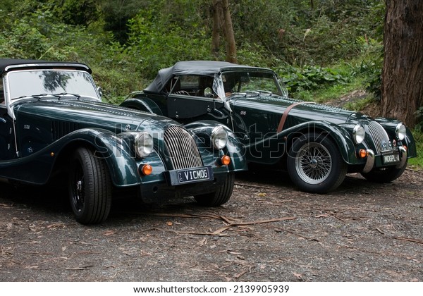 Melbourne, Australia - March 23, 2022:  Two elegant\
black Morgan Plus cars.  The Morgan Motor Company is a historic\
British car manufacturer that produces hand-crafted retro sports\
cars from the past.