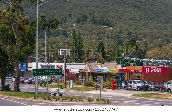 Melbourne, Australia - November 15, 2009: Outside\
city on road to Mount Dandenong, in Montrose community: local post\
office ansd small retail businesses with green forested flank of\
hill in back.
